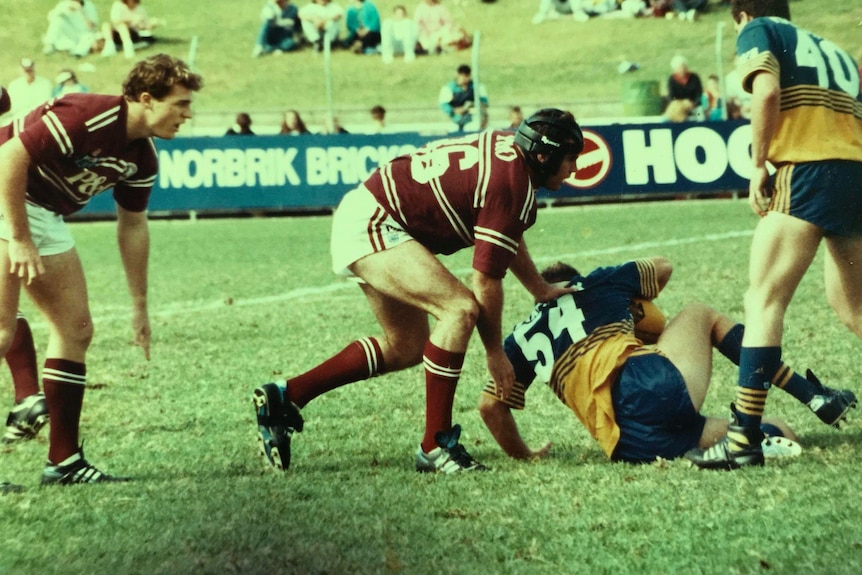 Man in marron rugby gear tackling another man in yellow and blue gear 