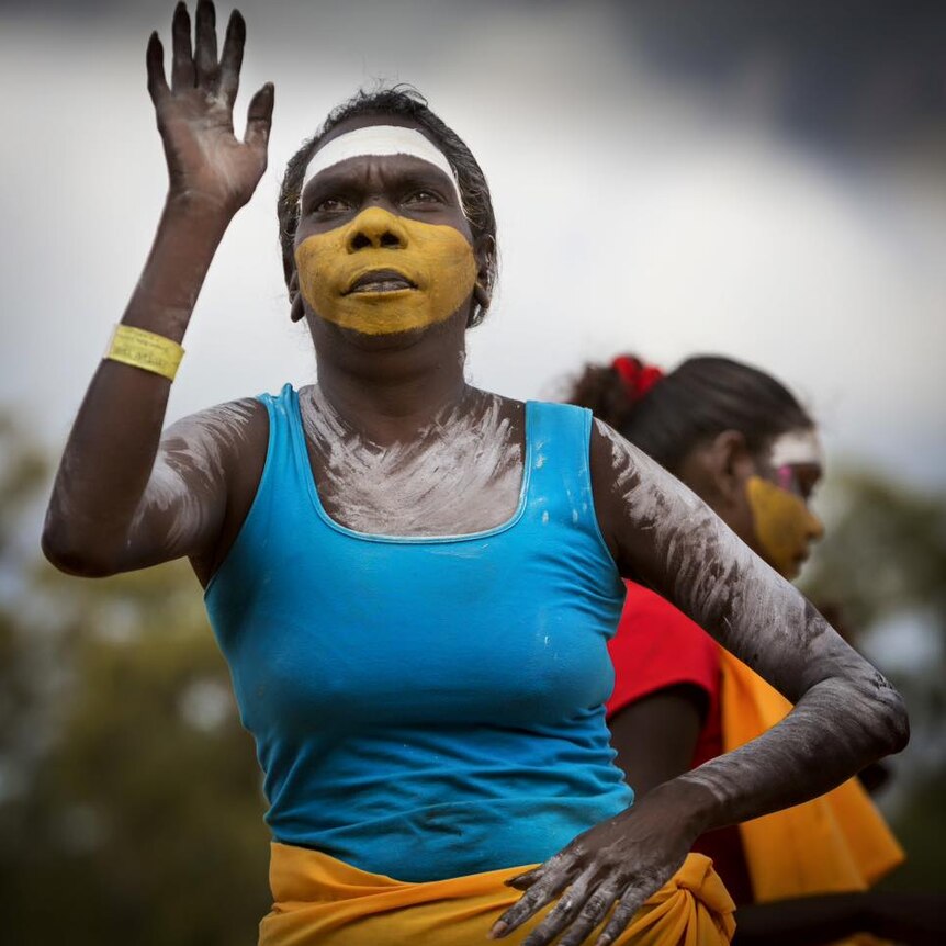 An Aboriginal woman, painted in yellow and white ochre, dancing.