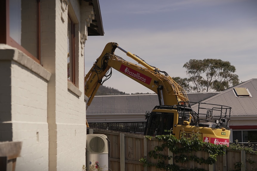 Excavator working at a house demolition site.