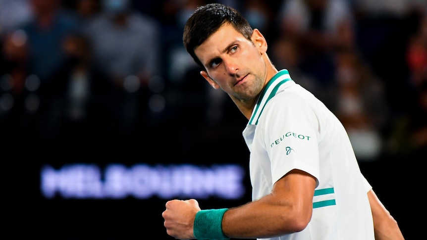 Dark haired man in green and white sports polo shirt looks over his shoulder