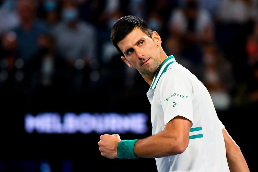 Dark haired man in green and white sports polo shirt looks over his shoulder