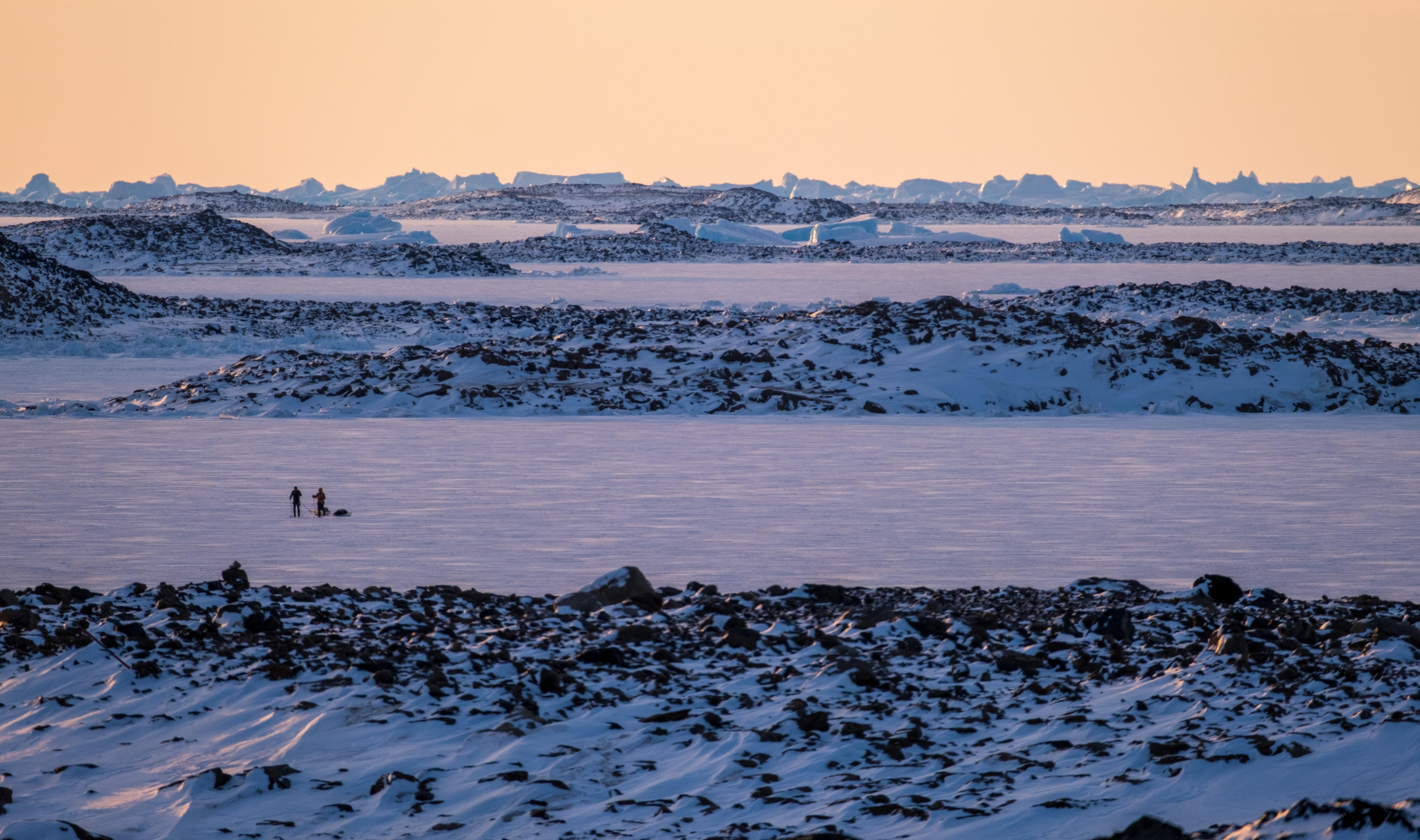 Two people walking on an icy surface in Antarctica.