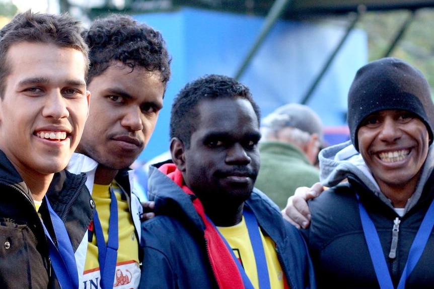 Four men standing together smiling.