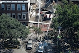 An aerial view shows water being squirted onto a partially destroyed building.