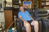 man in a blue shirt sitting in a chair with a walking cane 