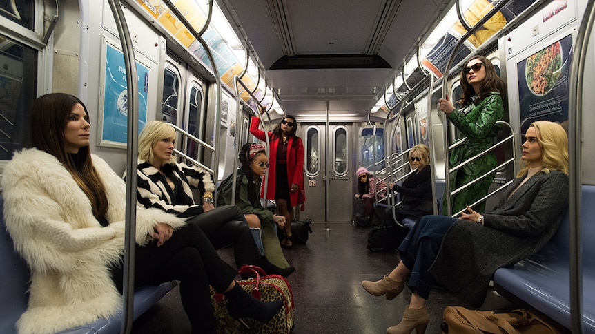 Colour photograph of Ocean's 8 cast riding in an empty subway carriage.