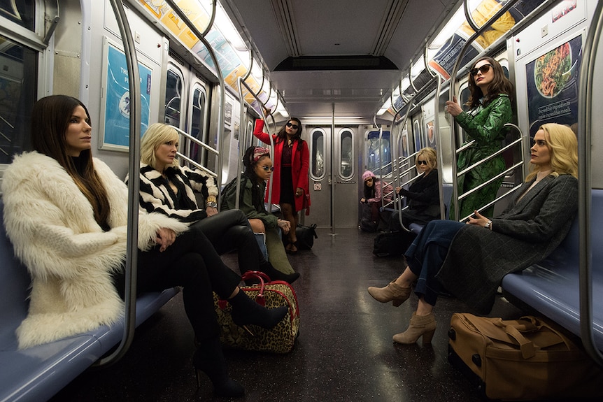 Colour photograph of Ocean's 8 cast riding in an empty subway carriage.