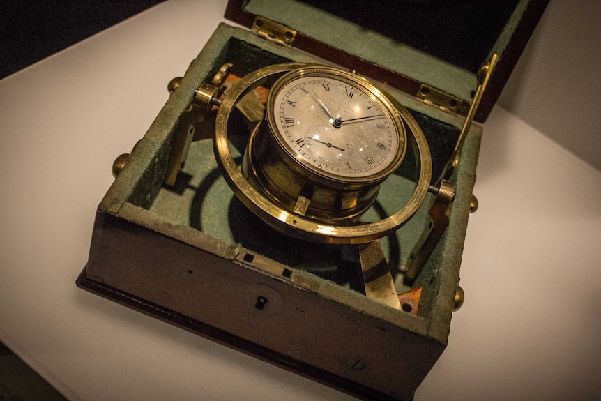 A golden chronometer in a box with an open lid
