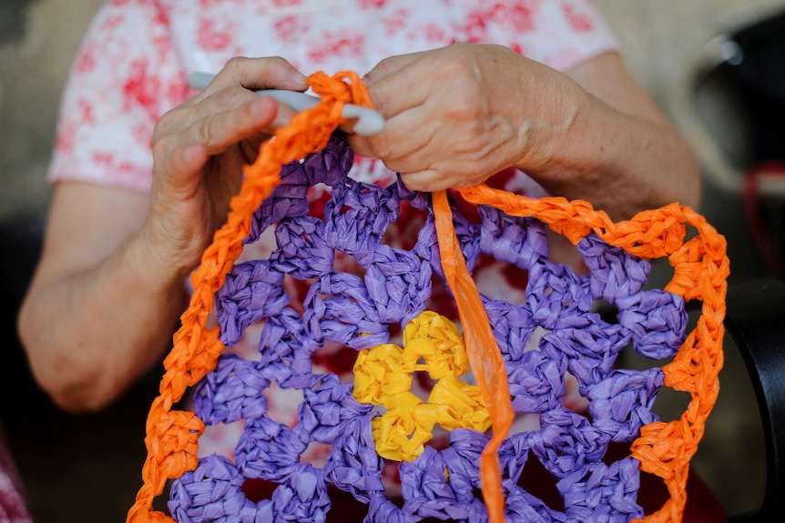 一个女人的手编织着一把由回收材料制成的雨伞，为西班牙的人们遮挡阳光。 