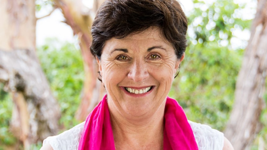 Close-up headshot of parenting expert Maggie Dent, standing in front of a tree and wearing a pink scarf.