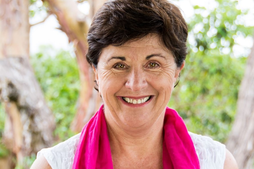 Close-up headshot of parenting expert Maggie Dent, standing in front of a tree and wearing a pink scarf.