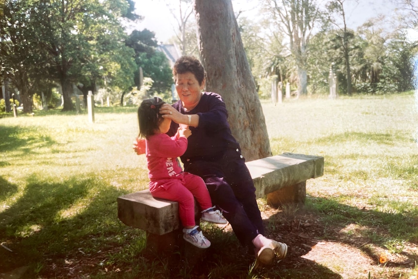 Naeun and her grandmother sitting on a park bench when Naeun was young.