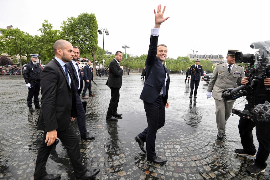 French President Emmanuel Macron waves as he arrives to attend a ceremony.