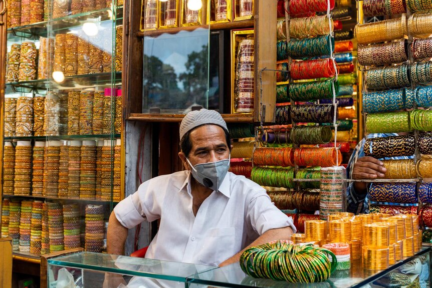 A man in a face mask stands in a bangle shop