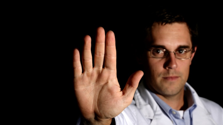 Man in white coat with hand raise in stop signal