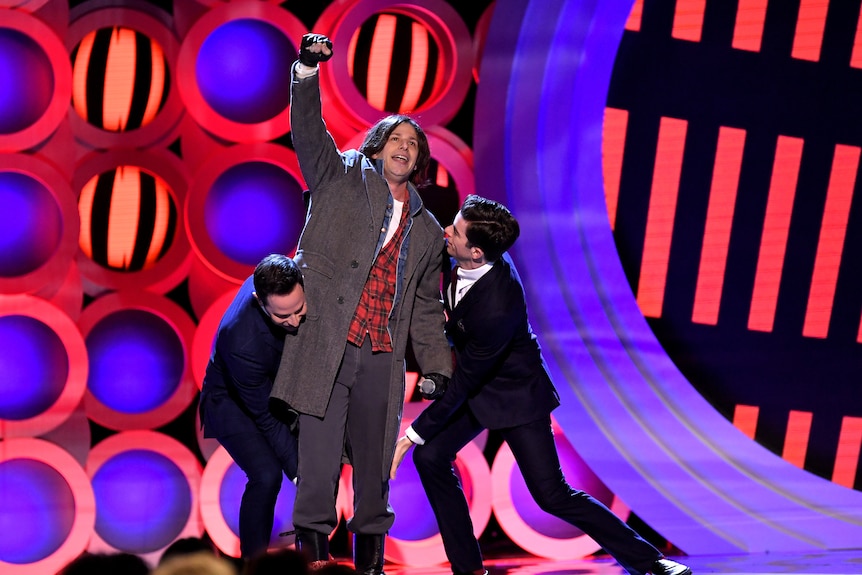 Co-hosts Nick Kroll and John Mulaney carry Andy Samberg offstage at the 2018 Independent Spirit Awards.