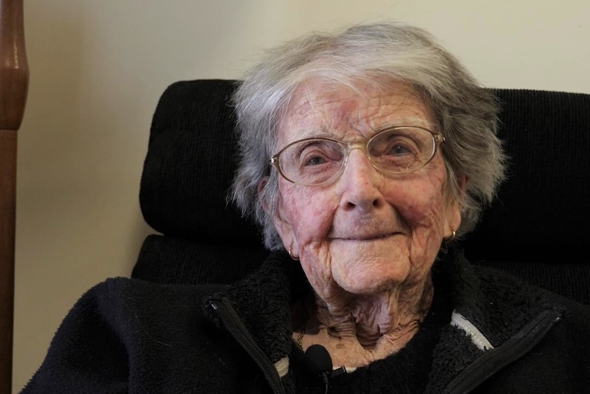 Elderly lady face closeup, wearing glasses smiling at camera