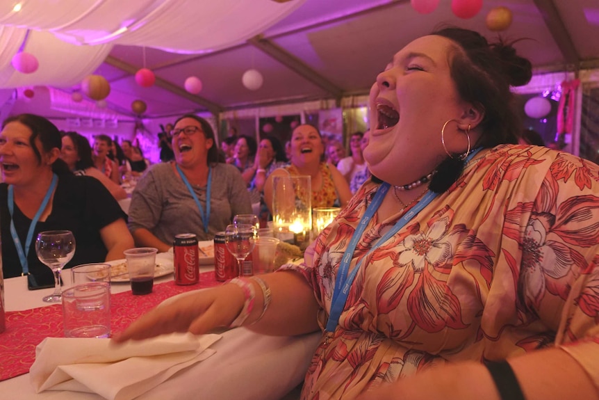 A woman laughing with other women around her