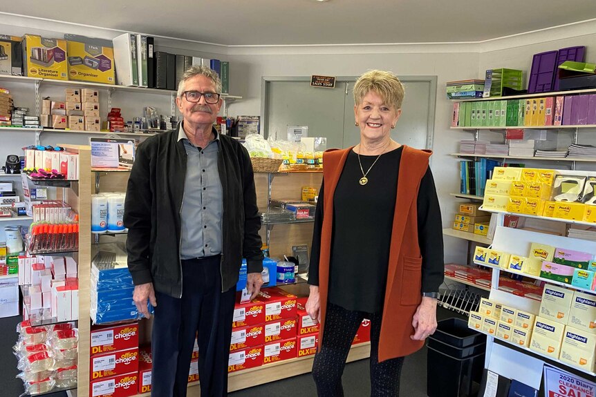 A man and a woman standing in a shop full of office supplies.