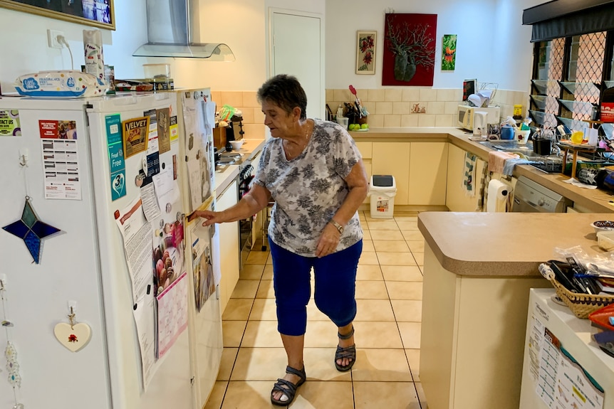 A woman in a kitchen reached for the fridge door