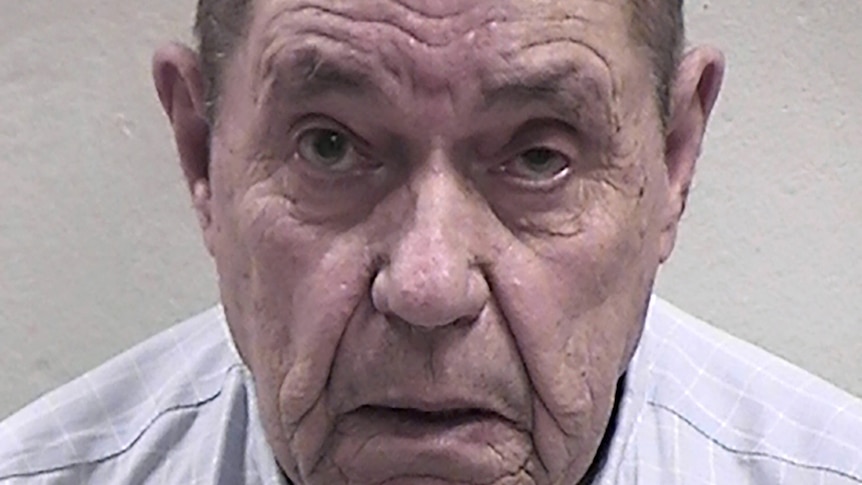 Mugshot of an old white man wearing a blue checkered shirt.
