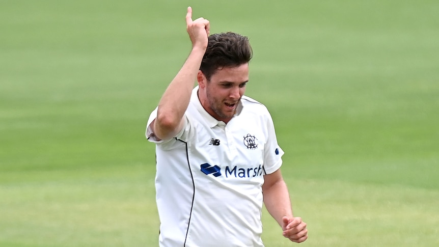 A Western Australian fast bowler raises his right hand as he celebrates a Sheffield Shield wicket against Queensland.