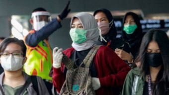 Indonesian women wearing head cover and mask in the crowd.