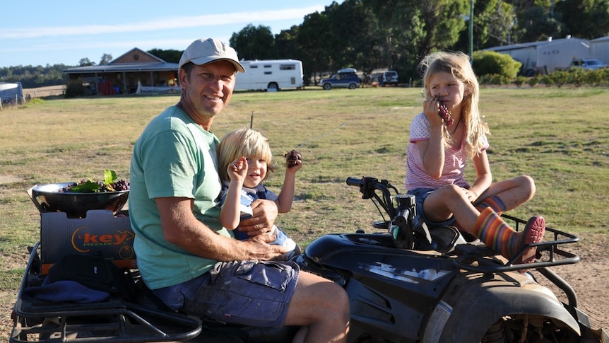 Rob Catania sits on a quad bike with his two children Jade and Henry.