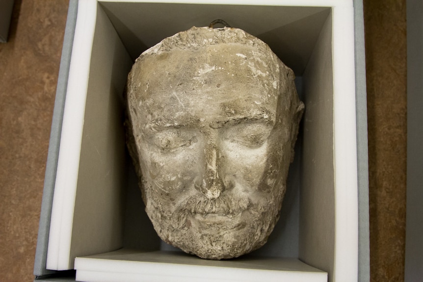 A box containing the cast of the face of a bearded man.
