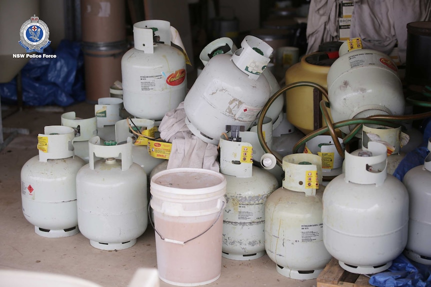 Gad cannisters sit piled on top of one another inside a shed.