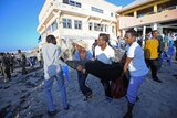 People carry away a dead body following a terrorist attack on Lido beach, Mogadishu