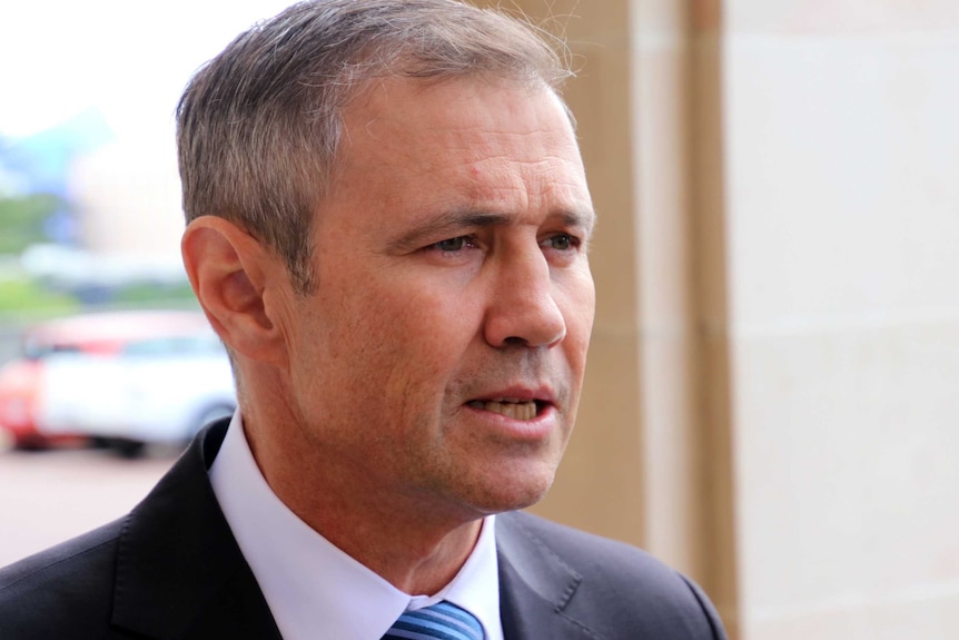 A tight head and shoulders shot of WA Health Minister Roger Cook speaking outdoors.