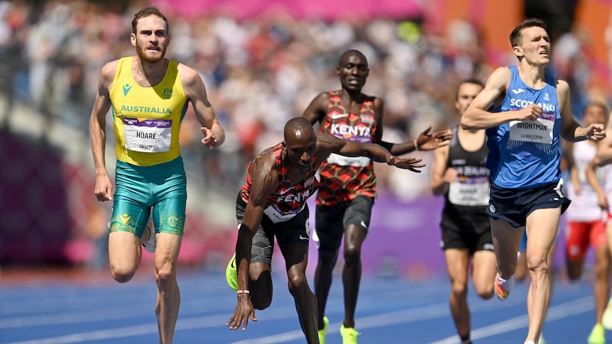 An Australian male 1,500 metres athlete crosses the line in first place as a Kenyan opponent stumbles.