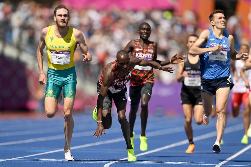 Un atleta masculino australiano de 1.500 metros cruza la línea en primer lugar cuando un oponente keniata tropieza.
