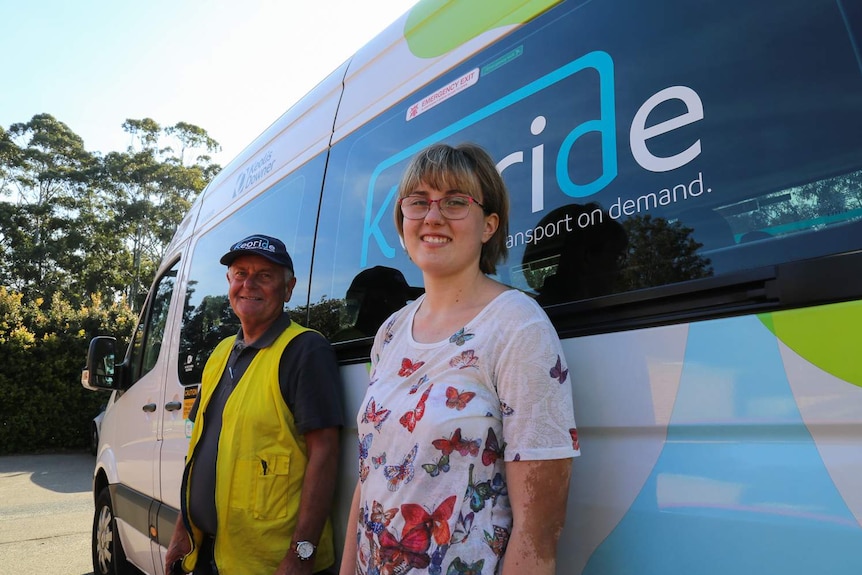 A man and a woman standing outside a passenger van.