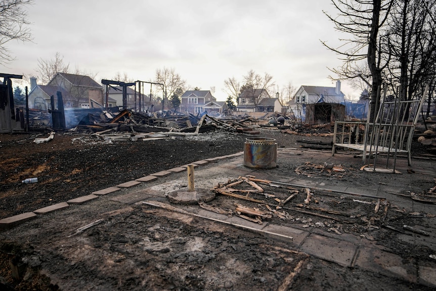 A group of homes burned to the ground still smoulder.