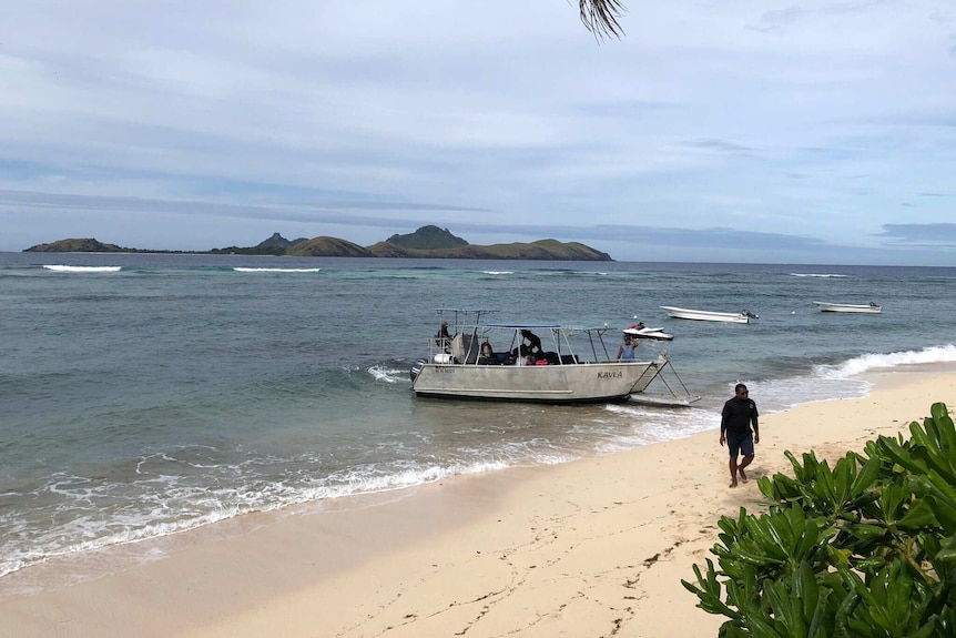 A boat on the coast of Fiji taking people away from the island.
