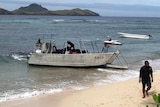 A boat on the coast of Fiji taking people away from the island.