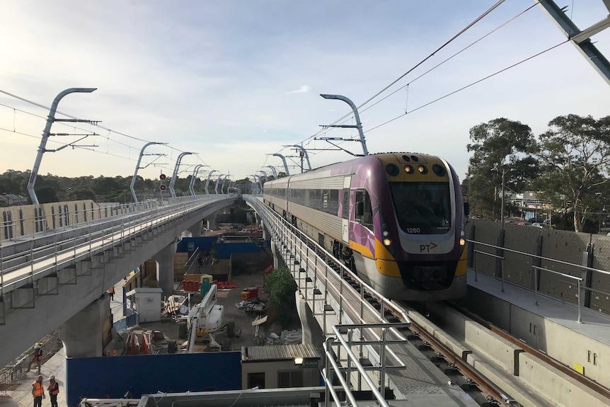 A V/Line train pulls into Noble Park station along a section of elevated rail.