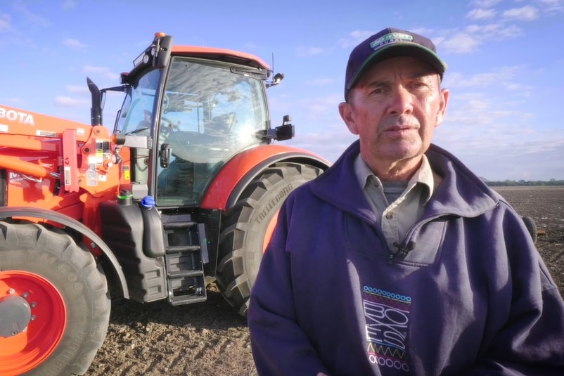 Lex Webb stands in front of his orange tractor