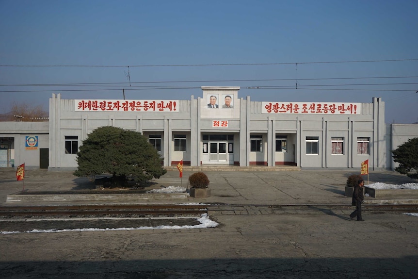 Propaganda banner and portraits of North Korea leaders at the front of a house in North Korea,