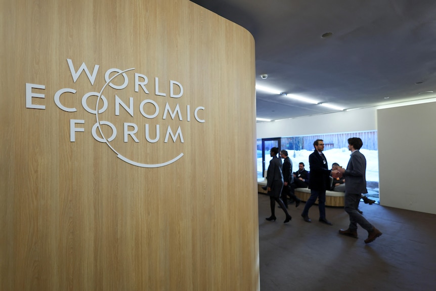 A World Economic Forum sign with people walking in the background