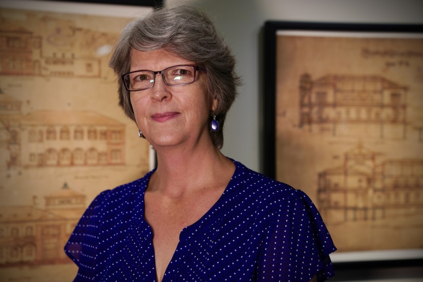 James Cook University curator Bronwyn McBurnie stands in front of some old architectural drawings