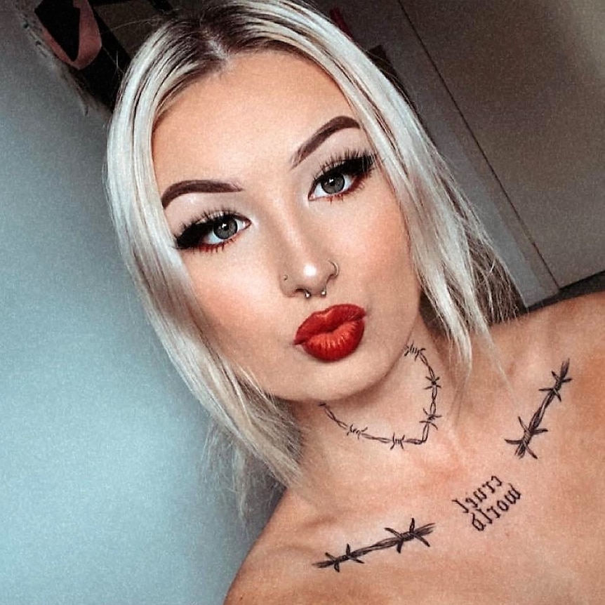 A young woman with tattoos on her neck taking a selfie.