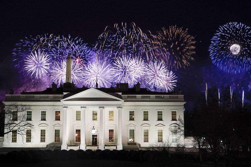 Different colours light up the sky over a white House.