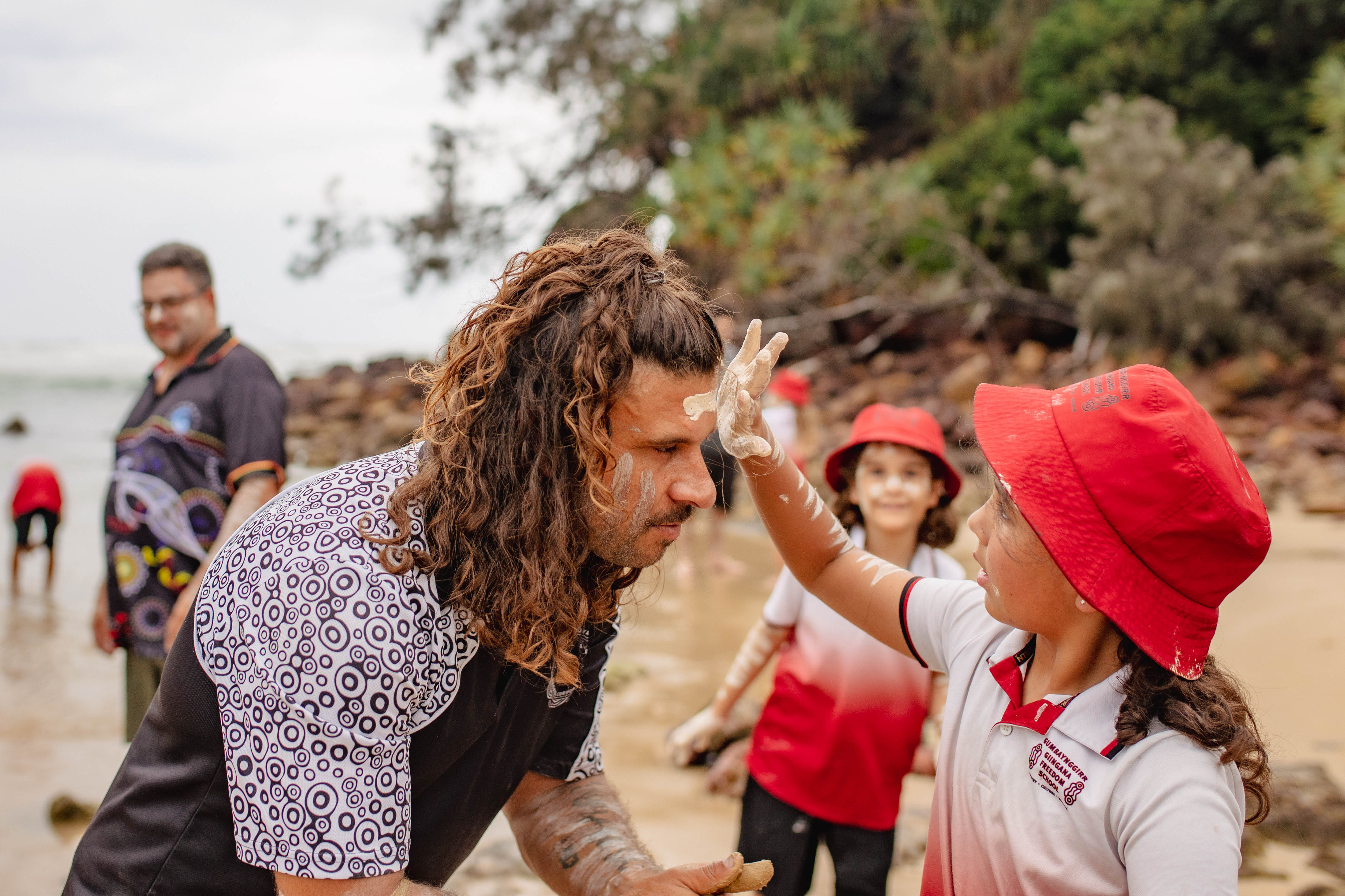 Young school kids puts traditional paint on teacher's face 