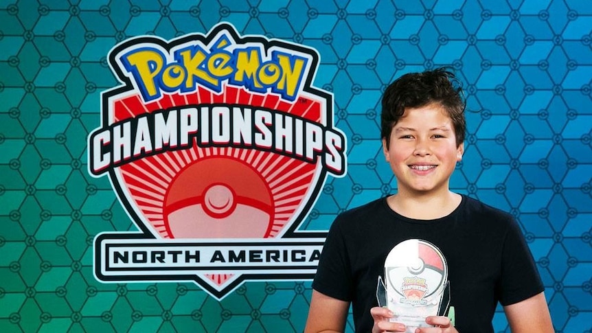 A boy in a black shirt holds a trophy.