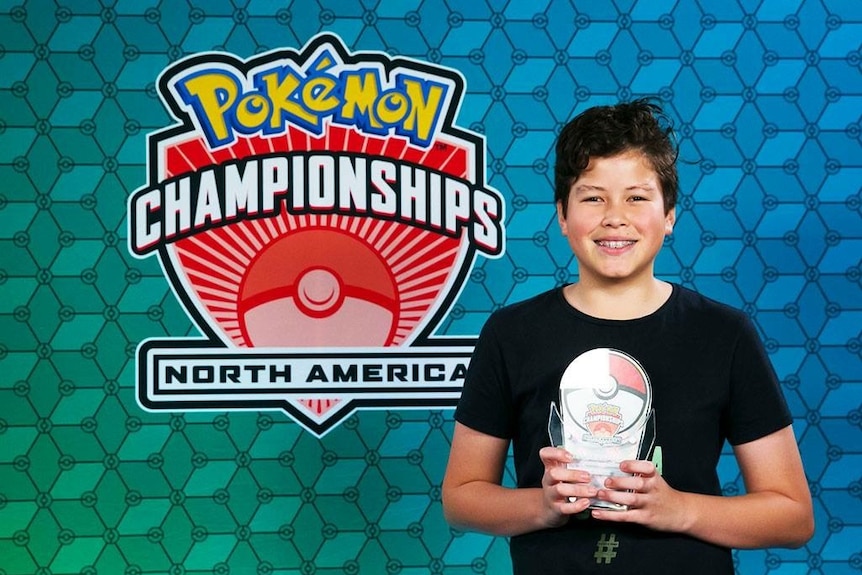 A boy in a black shirt holds a trophy.