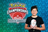 A boy in a black shirt holds a trophy.