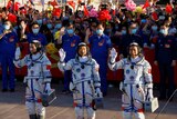 Chinese astronauts Tang Hongbo, Nie Haisheng and Liu Boming wave before the launch of the Long March-2F Y12 rocket.